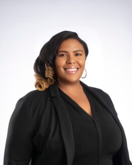 Photo of Executive Recruiter Kayla Jackson-Gougisha. Photo has a white background and she is wearing a black top and blazer